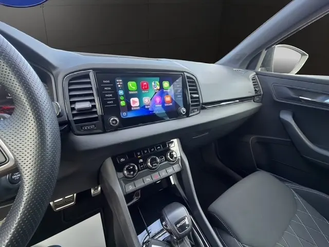 Vue intérieure côté passager du tableau de bord noir du Skoda Karoq 2025 avec écran tactile et volant cuir multifonctions.