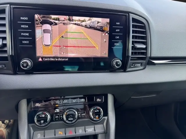Vue rapprochée de l’écran tactile central du Skoda Karoq noir 2025 affichant la caméra de recul avec lignes de guidage colorées.