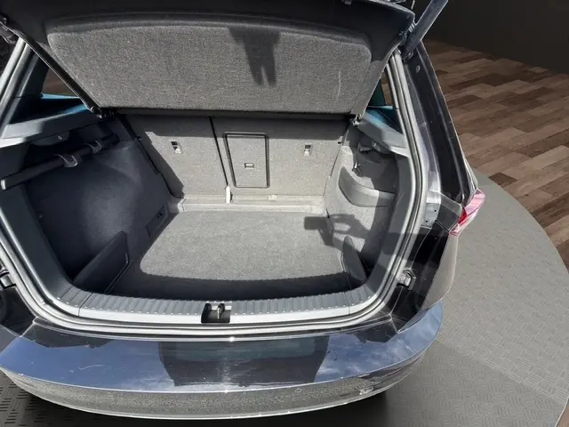 Coffre ouvert vu de l'arrière d'un Skoda Karoq noir 2025, montrant un espace de chargement propre et spacieux.