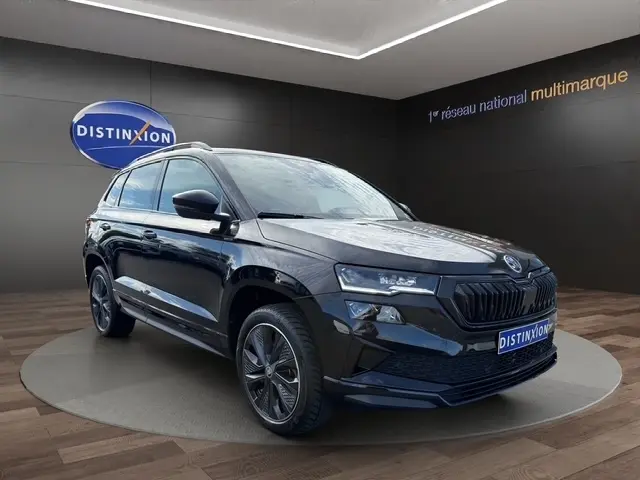 Vue 3/4 avant droite d'un Skoda Karoq noir 2025 avec calandre noire et jantes alliage distinctives.