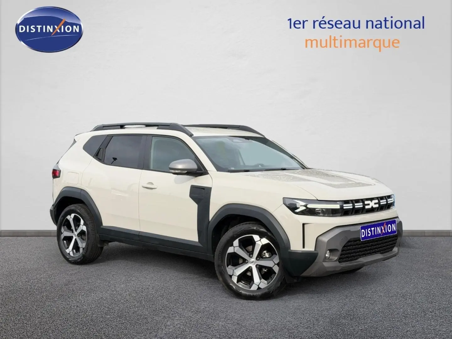 SUV Dacia Duster 2025 couleur Sandstone en vue 3/4 avant, avec jantes alliage et barres de toit noires.