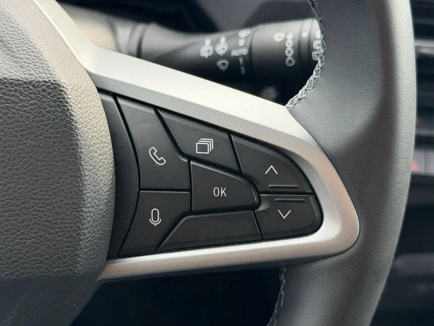 Gros plan sur les commandes multifonctions noires du volant du Dacia Duster 2025, finition Sandstone.