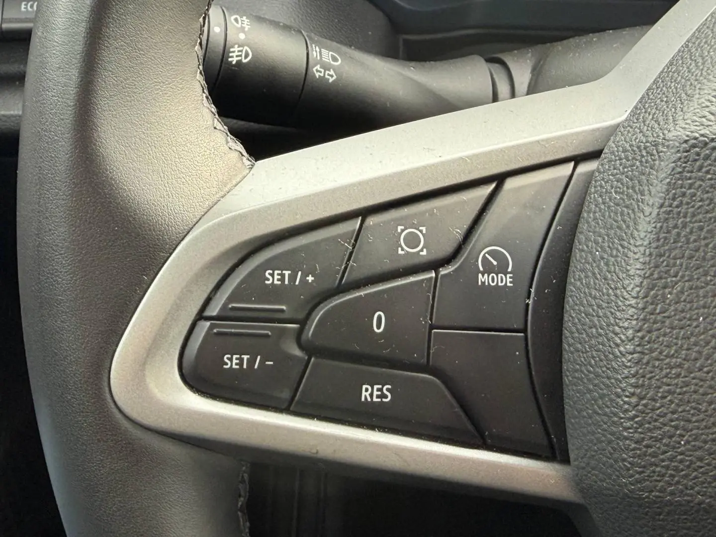 Gros plan sur les commandes multifonctions côté gauche du volant du Dacia Duster 2025 couleur Sandstone.