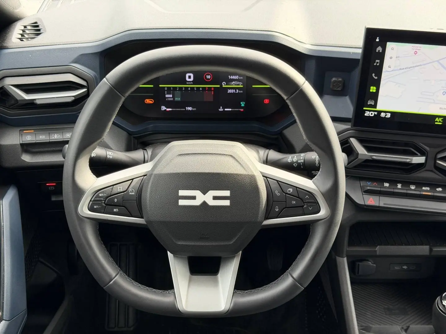 Vue frontale du volant multifonction noir et gris du Dacia Duster 2025 avec tableau de bord numérique et écran tactile GPS.