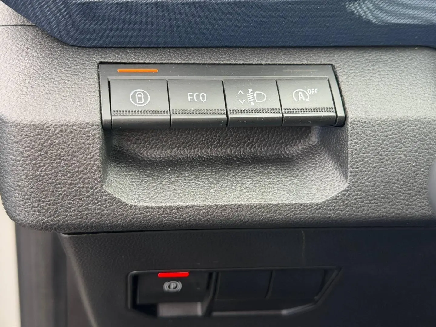 Détail des commandes de tableau de bord noir du Dacia Duster 2025, boutons ECO et aide au démarrage visibles.