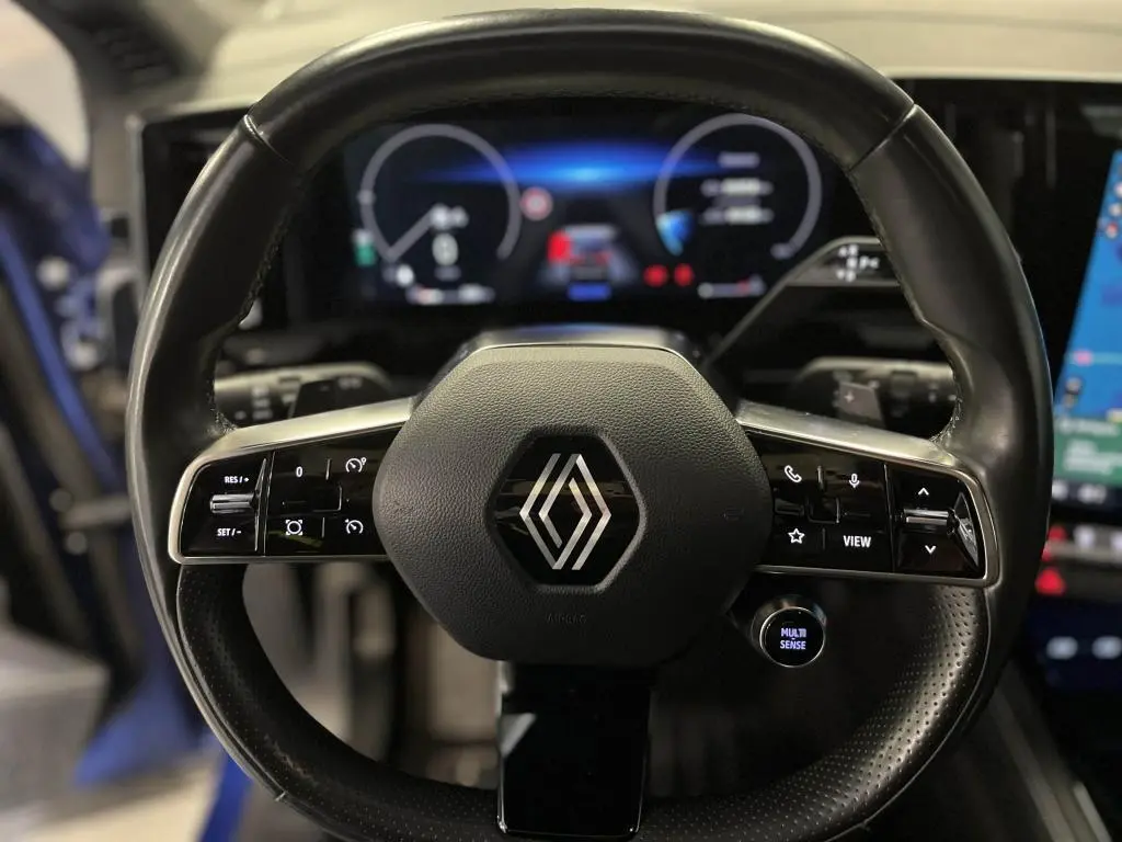 Volant cuir noir de Renault Austral 2023 avec commandes intégrées et tableau de bord numérique lumineux en arrière-plan.
