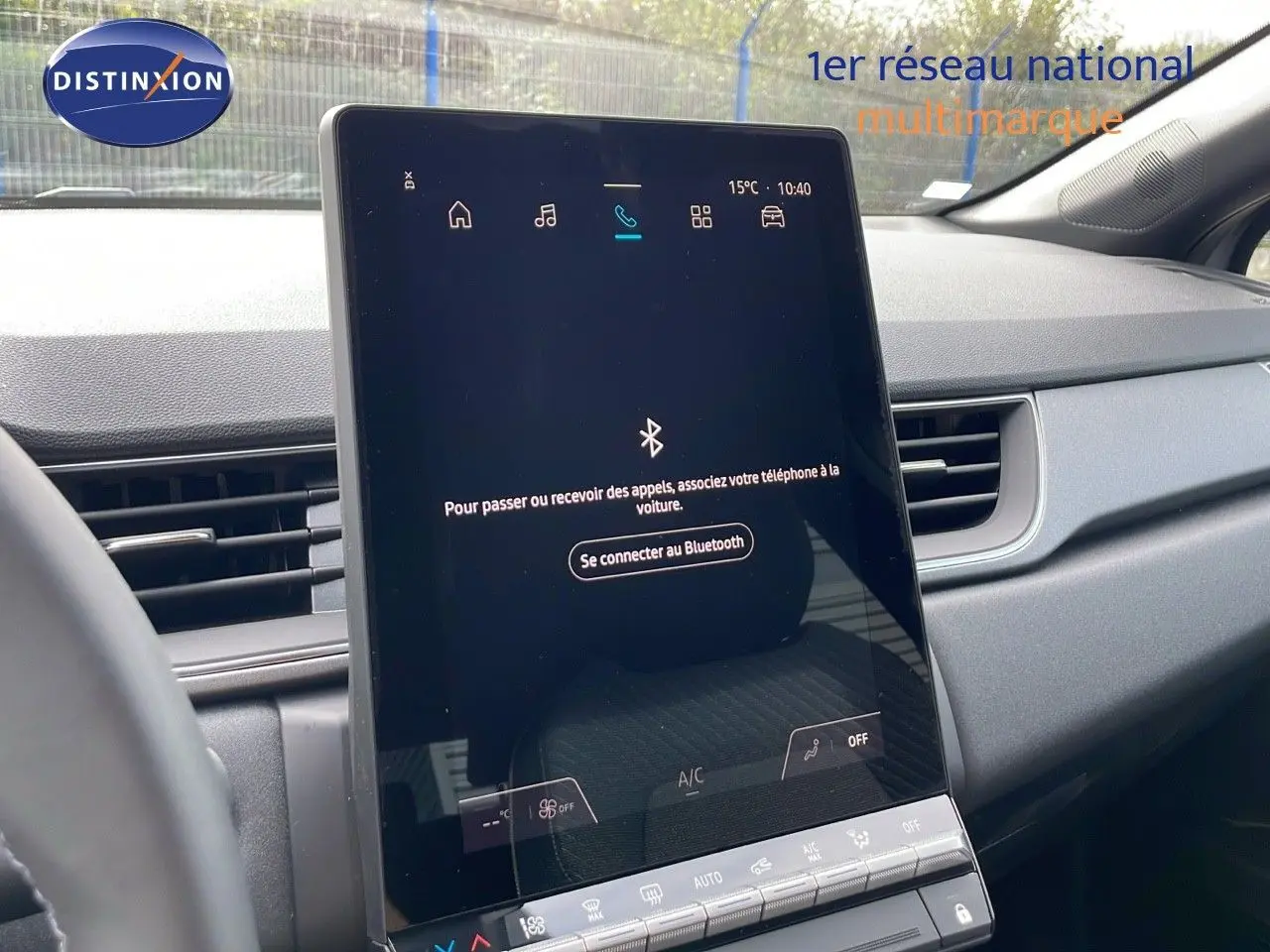 Écran tactile central allumé dans l’habitacle gris du Renault Captur E-Tech hybride 2025, vue de face côté conducteur.