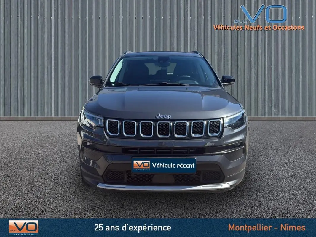 Vue frontale d'un Jeep Compass gris 2023 avec calandre à sept fentes et phares LED allumés.