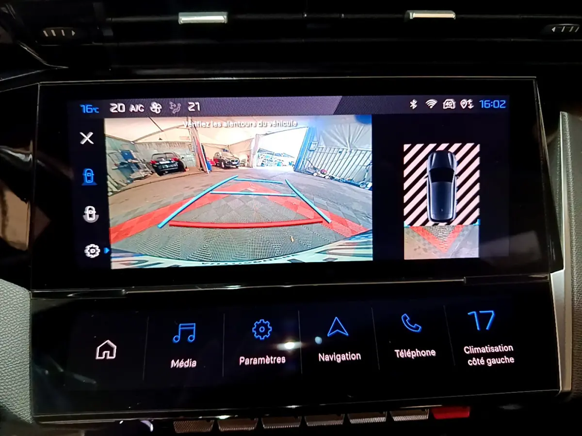 Écran tactile intérieur montrant la caméra de recul et l'aide au stationnement du Peugeot 308 PHEV blanc.