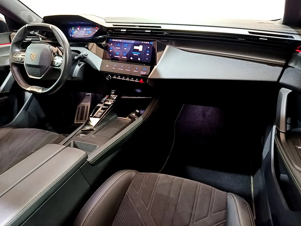 Intérieur Peugeot 308 PHEV 180 GT 2022 vu côté passager, tableau de bord moderne avec écran tactile et volant cuir.