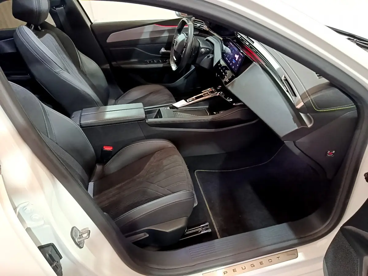Intérieur côté conducteur de la Peugeot 308 PHEV 180 GT blanc, avec sièges noirs et tableau de bord digital.