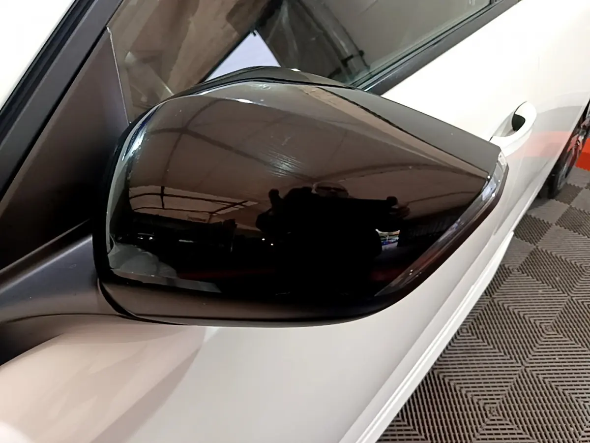 Rétroviseur noir brillant côté gauche d'une Peugeot 308 PHEV 180 E-EAT8 GT blanche vue en gros plan.