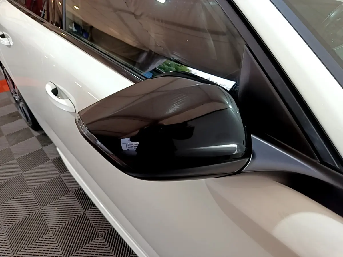 Gros plan sur le rétroviseur noir côté gauche d'une Peugeot 308 PHEV 180 E-EAT8 GT blanche de 2022.