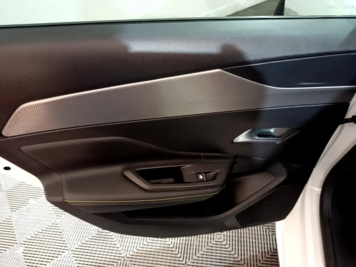 Vue rapprochée de la porte côté droit blanche du Peugeot 308 PHEV 180 E-EAT8 GT avec garniture noire et insert gris.