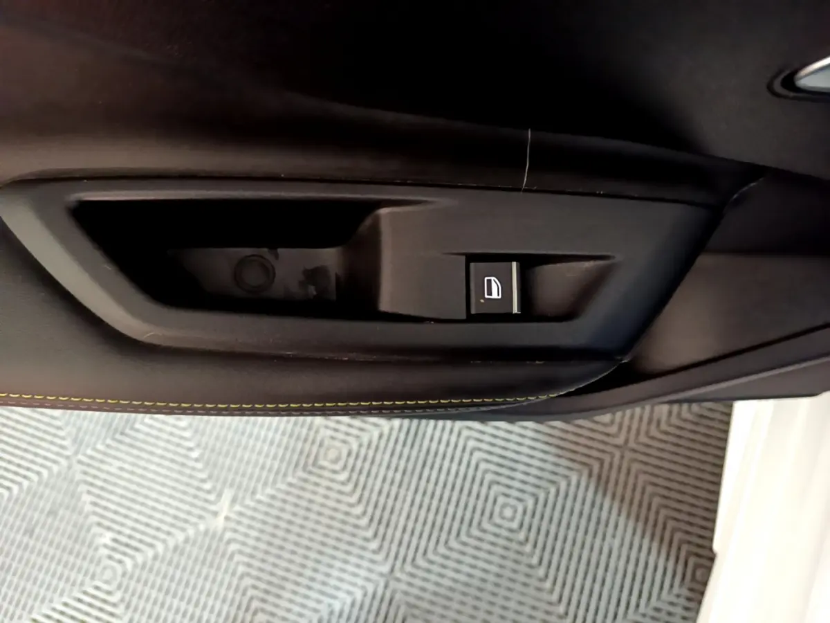 Bouton de verrouillage de porte noir sur la garniture intérieure côté conducteur d'une Peugeot 308 PHEV blanche.