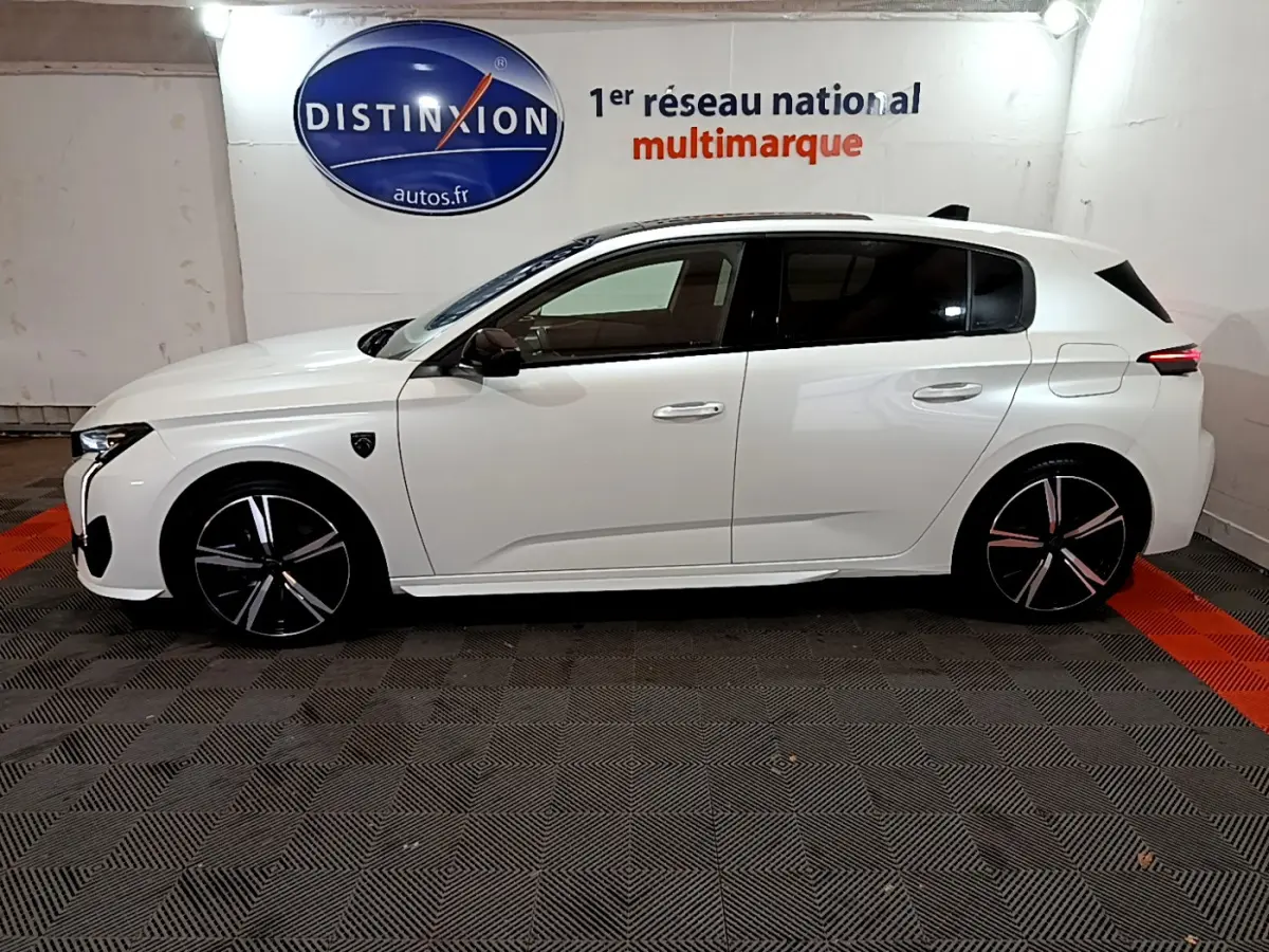 Profil côté gauche d'une Peugeot 308 PHEV 180 E-EAT8 GT blanche, avec jantes noires et détails modernes visibles.