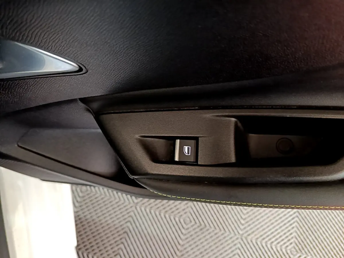 Gros plan sur la commande de lève-vitre côté conducteur dans l'intérieur noir de la Peugeot 308 PHEV 180 GT blanche.