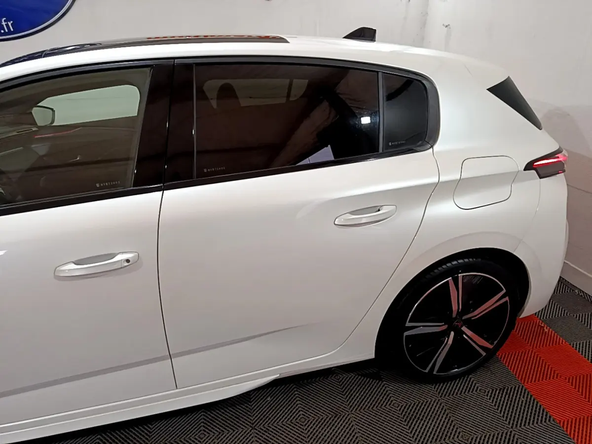 Vue latérale droite d'une Peugeot 308 PHEV 180 E-EAT8 GT blanche avec jantes noires et vitres teintées.