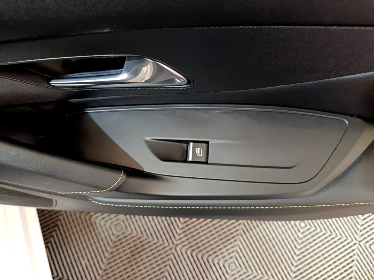 Bouton de commande de lève-vitre sur la porte intérieure côté gauche d'une Peugeot 308 PHEV blanche.
