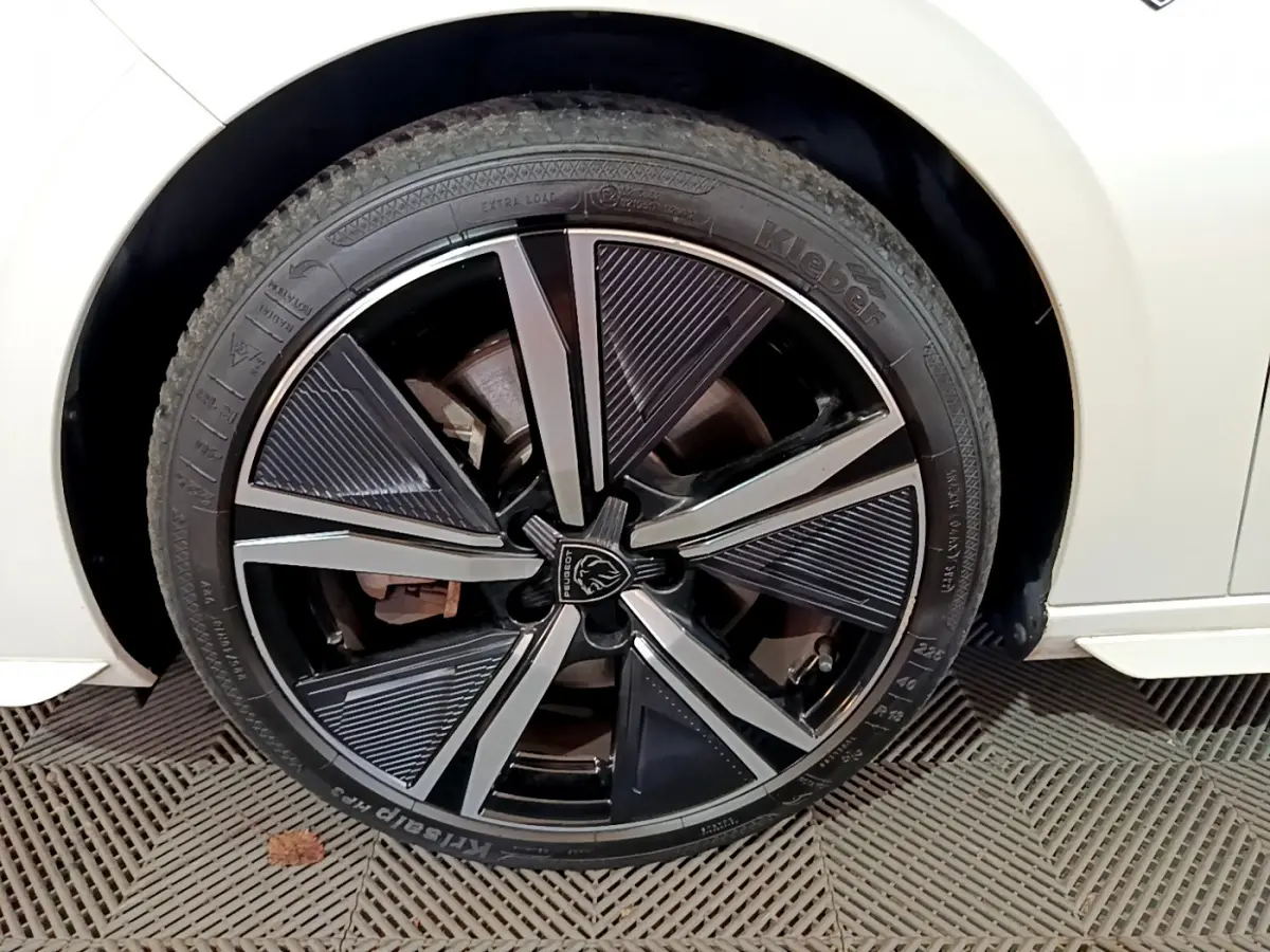 Gros plan sur la roue avant gauche de la Peugeot 308 PHEV 180 E-EAT8 GT blanche avec jante noire et argentée design moderne.