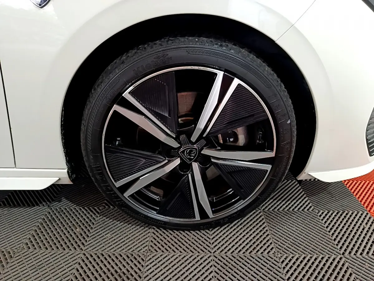 Gros plan sur la roue avant droite noire et argentée d'une Peugeot 308 PHEV 180 E-EAT8 GT blanche.