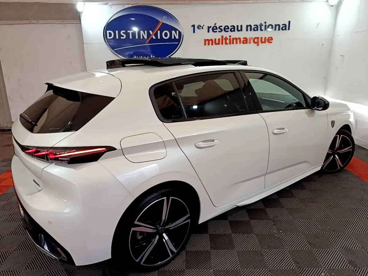 Peugeot 308 PHEV 180 GT blanc vue 3/4 arrière droit avec toit ouvrant et feux LED allumés.