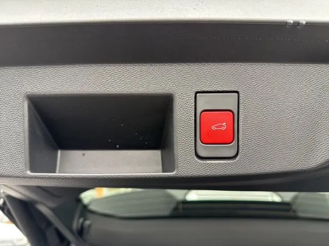 Gros plan sur le bouton rouge d'ouverture du hayon motorisé du Citroën C5 Aircross gris platinium, vue intérieure arrière.