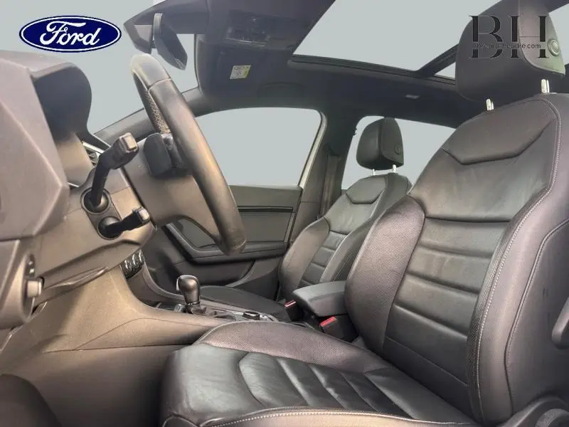 Vue intérieure côté conducteur du SEAT Ateca 2020 avec sièges sport en cuir noir et toit panoramique.