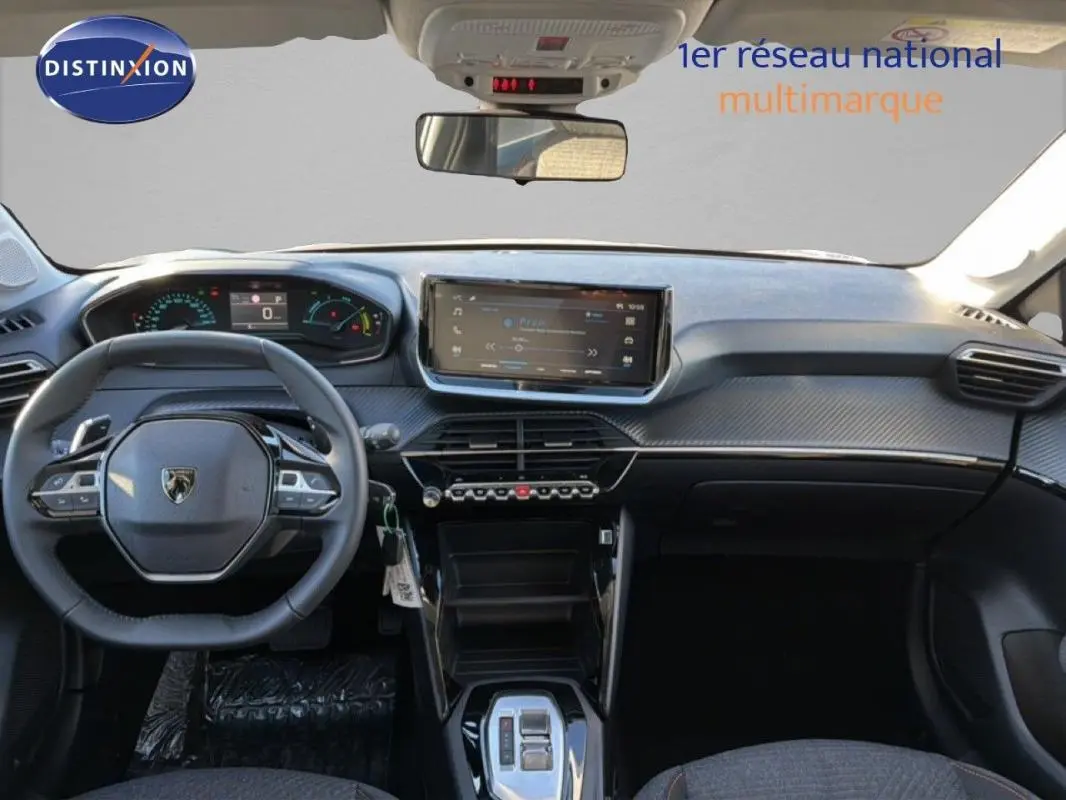 Vue intérieure avant du Peugeot 208 gris 2025, tableau de bord avec écran tactile et volant cuir multifonction.