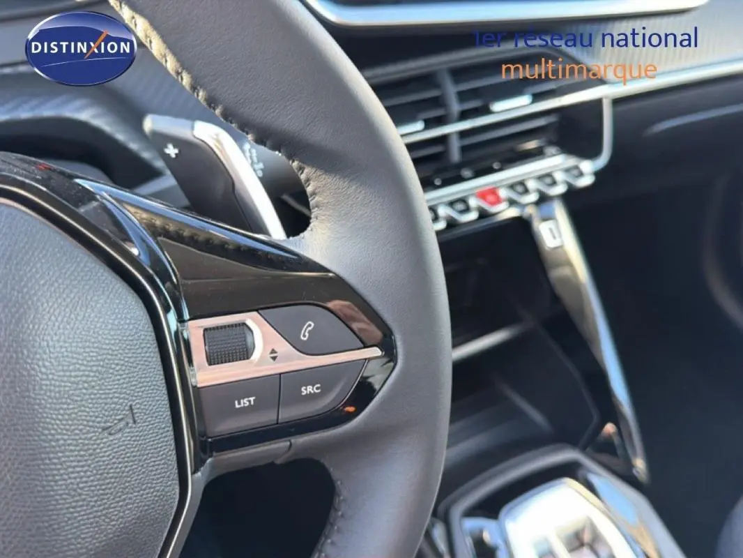 Gros plan sur le volant cuir de la Peugeot 208 gris, avec commandes intégrées et palettes au volant visibles.