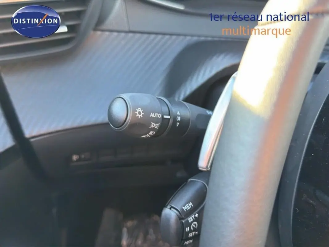 Détail du commodo d'éclairage et du volant cuir gris à palettes dans l'habitacle d'une Peugeot 208 gris 2025.