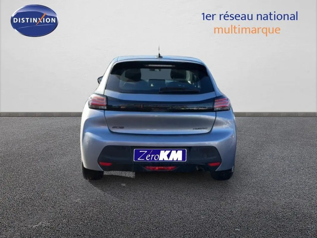 Vue arrière d'une Peugeot 208 gris 1.2 Hybrid 100ch avec feux LED et logo noir brillant sur un sol goudronné.
