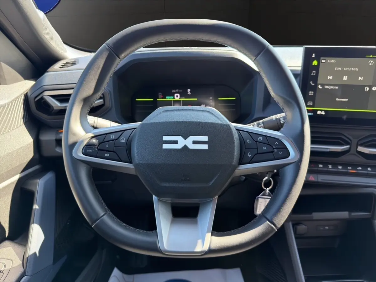 Volant cuir synthétique multifonctions au centre du tableau de bord du Dacia Duster gris foncé 2025, vue de face.