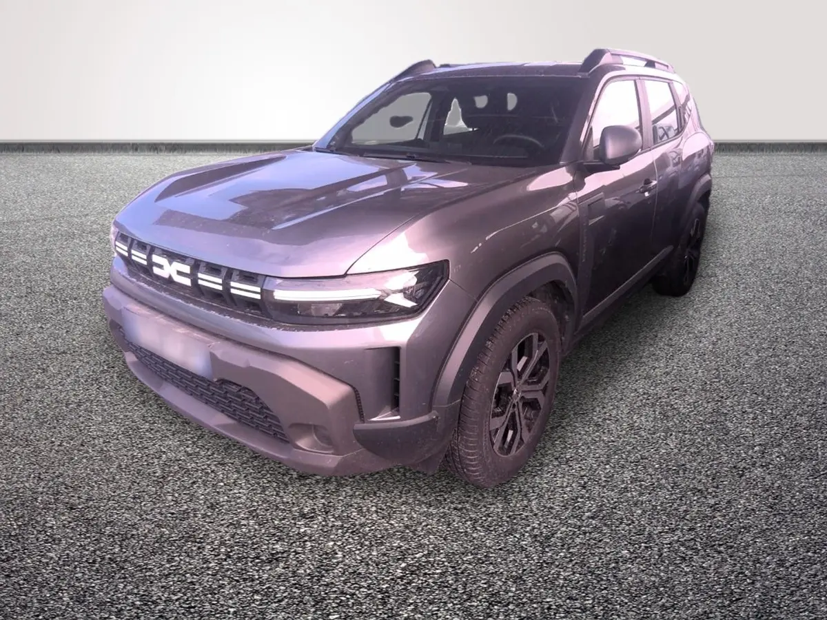 Dacia Duster gris foncé en 3/4 avant droit, avec calandre lumineuse et jantes noires distinctives.