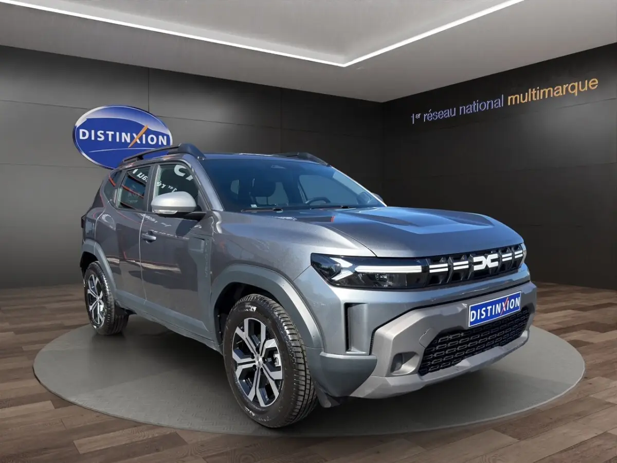 Dacia Duster gris foncé en 3/4 avant droit, avec calandre moderne et jantes alliage distinctives.