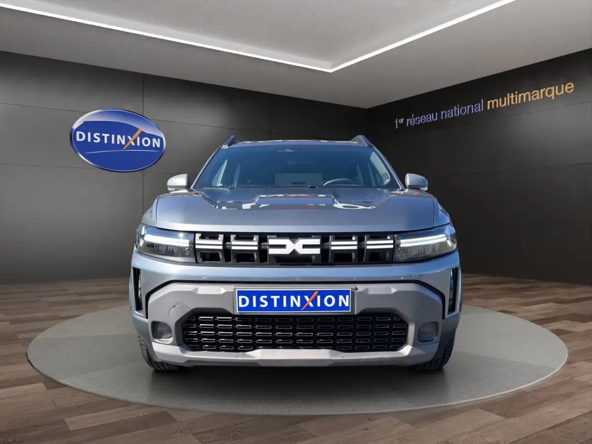 Vue frontale d'un Dacia Duster Expression Hybrid 140 gris foncé avec calandre marquée et feux LED fins.