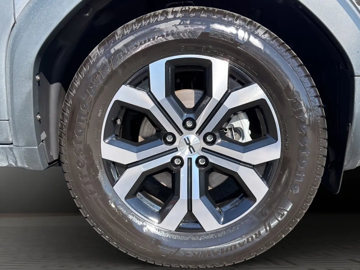 Gros plan sur la roue avant droite du Dacia Duster gris foncé avec jante alliage à design hexagonal.