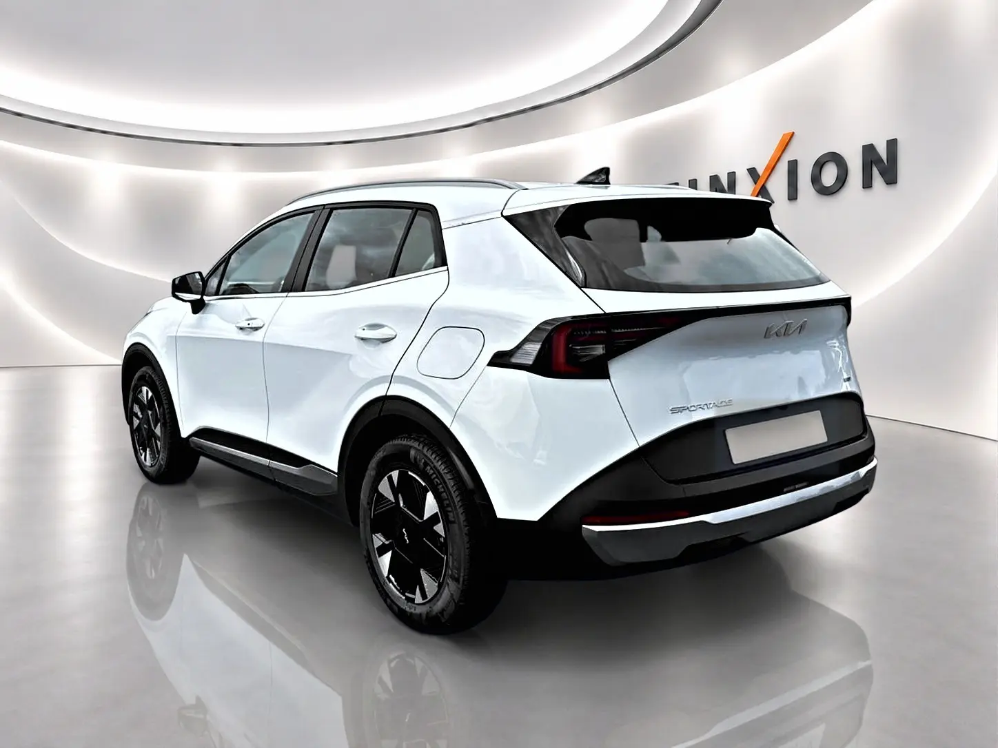 KIA Sportage 1.6 hybride blanc vu en 3/4 arrière droit, avec jantes alu noires et feux arrière LED distinctifs.