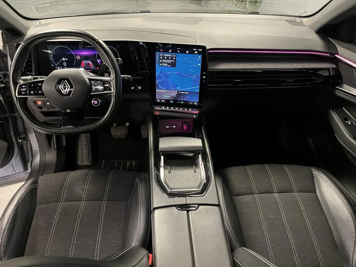 Intérieur avant du Renault Austral 2023, tableau de bord avec écran tactile vertical et éclairage d'ambiance violet.