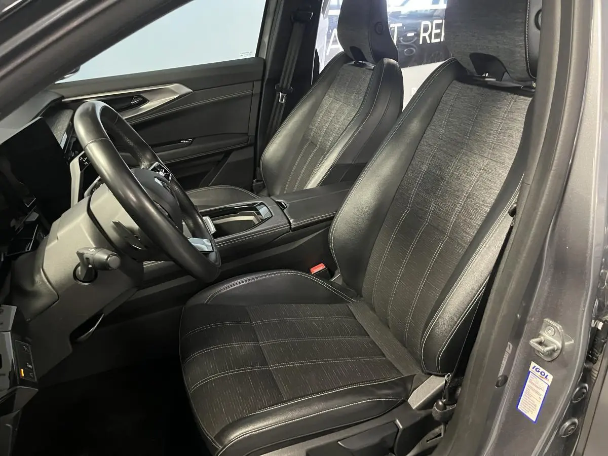 Vue intérieure côté conducteur du Renault Austral gris, sièges en simili-cuir noir avec surpiqûres argent et volant cuir.