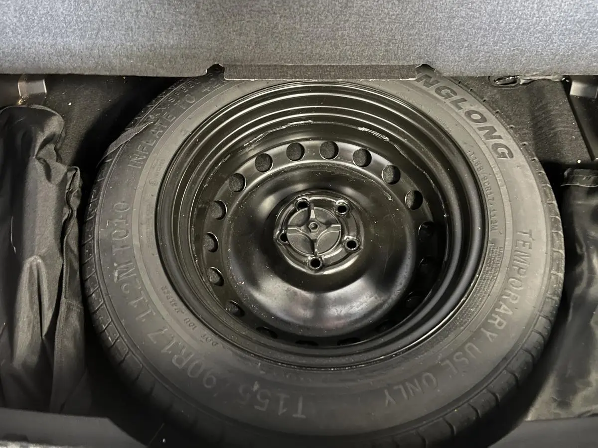 Gros plan sur la roue de secours galette noire du coffre d'un Renault Austral gris 2023.