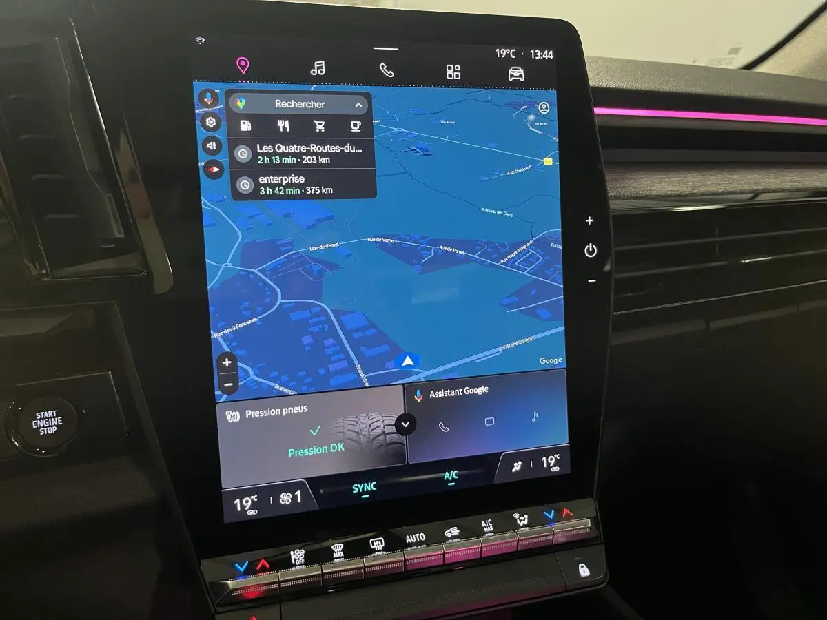 Écran tactile central du Renault Austral 2023 avec navigation et commandes climatisation, ambiance lumineuse rose visible.