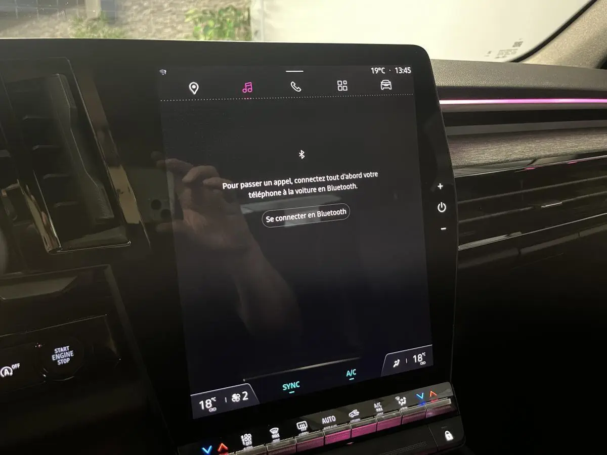 Écran tactile central du tableau de bord du Renault Austral 2023 avec ambiance lumineuse rose et inserts gris.
