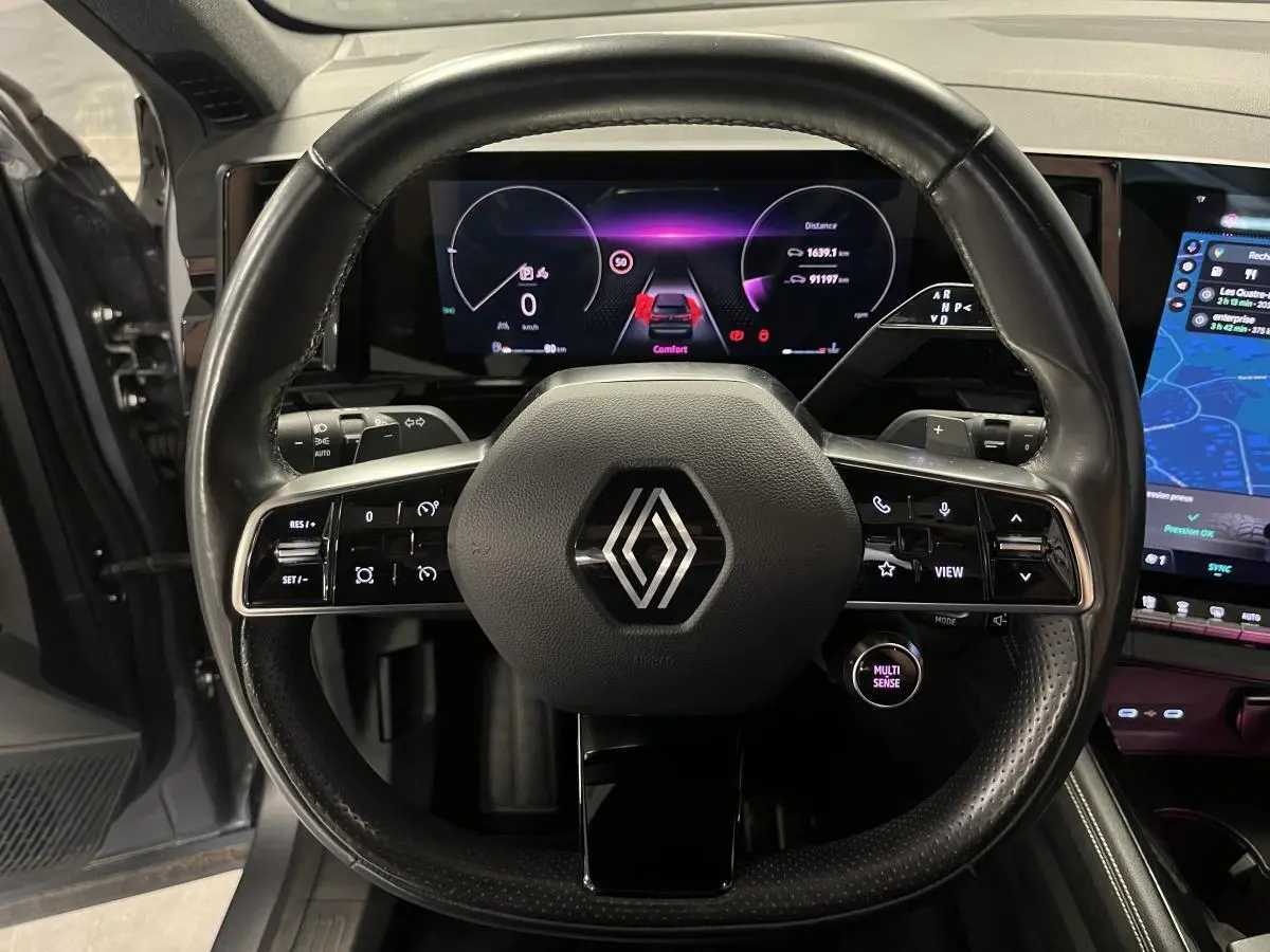 Vue frontale du volant cuir noir avec commandes intégrées du Renault Austral 2023, tableau de bord numérique et écran tactile visibles.