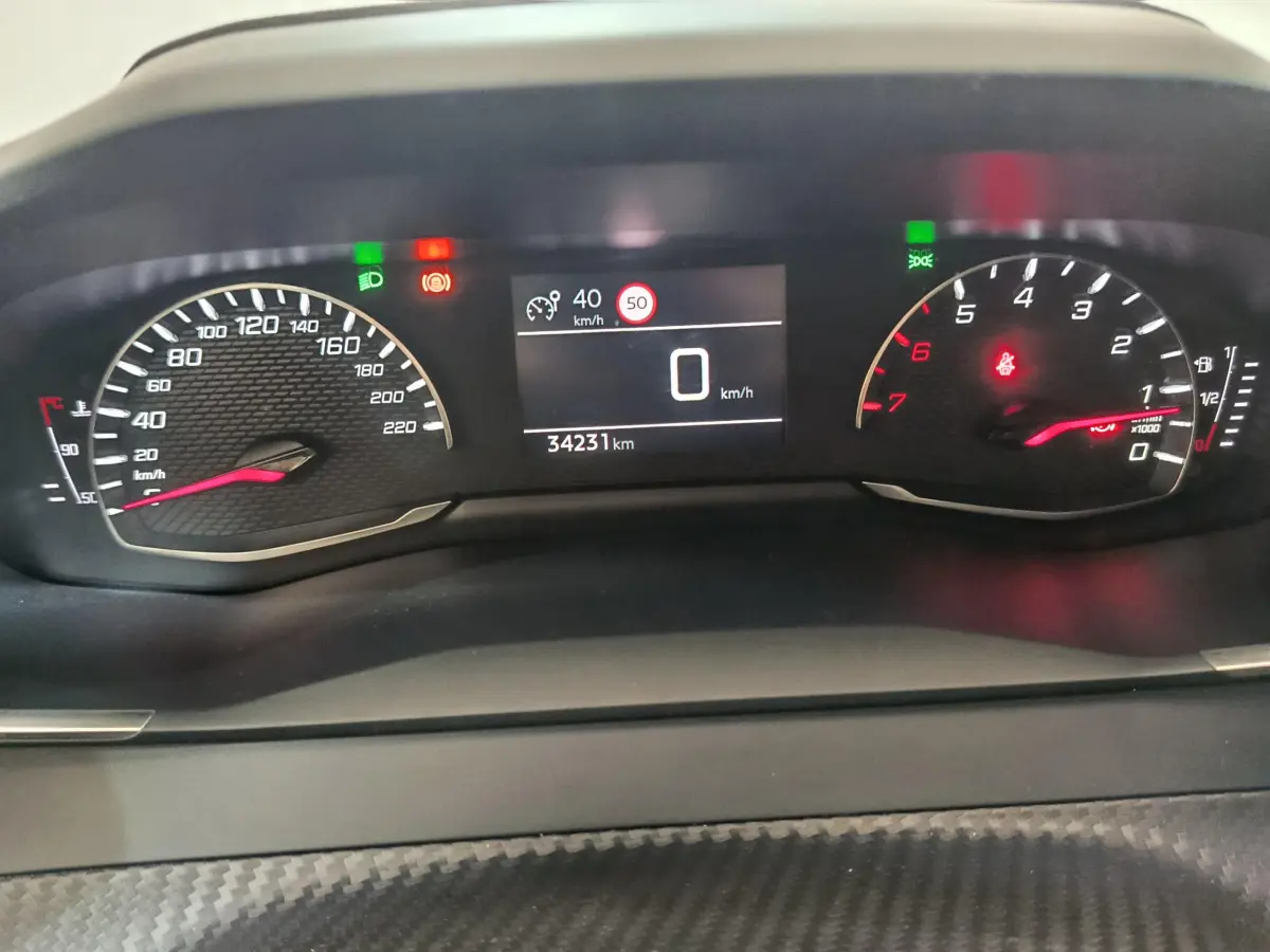 Tableau de bord de Peugeot 208 PureTech 100, affichage numérique central et compte-tours à aiguille, intérieur noir.