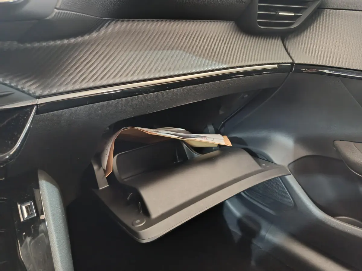 Gros plan sur la boîte à gants ouverte côté passager du Peugeot 208 blanc, soulignant la finition intérieure moderne.