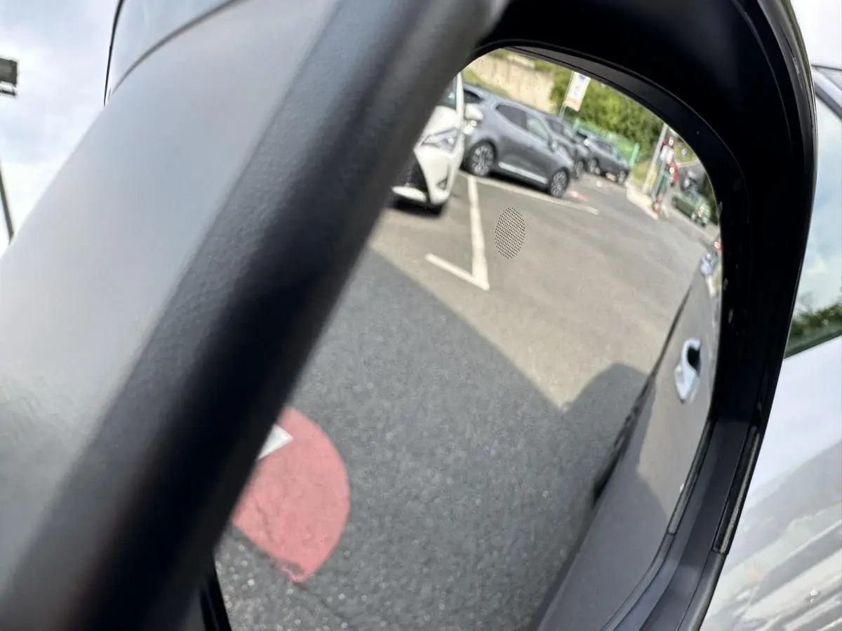 Reflet dans le rétroviseur droit d'un Peugeot 3008 gris Artense, vue partielle du côté droit du véhicule.