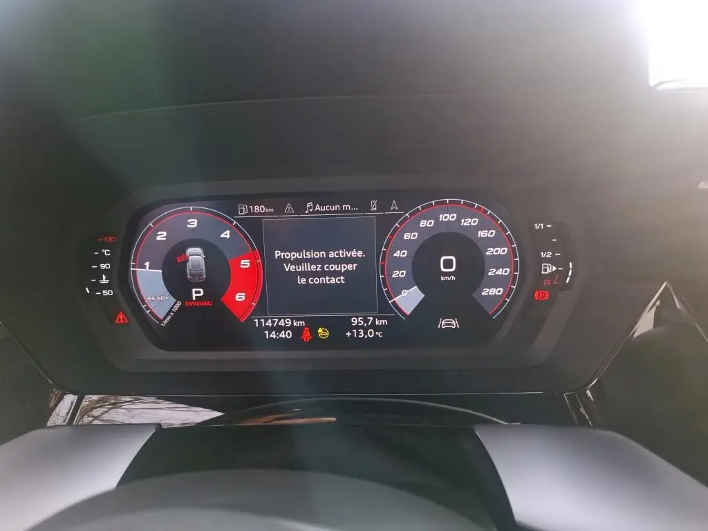 Vue rapprochée du tableau de bord numérique d'une Audi A3 bleu 2.0 TDI 2022 affichant la vitesse à 0 km/h et un message d'alerte.