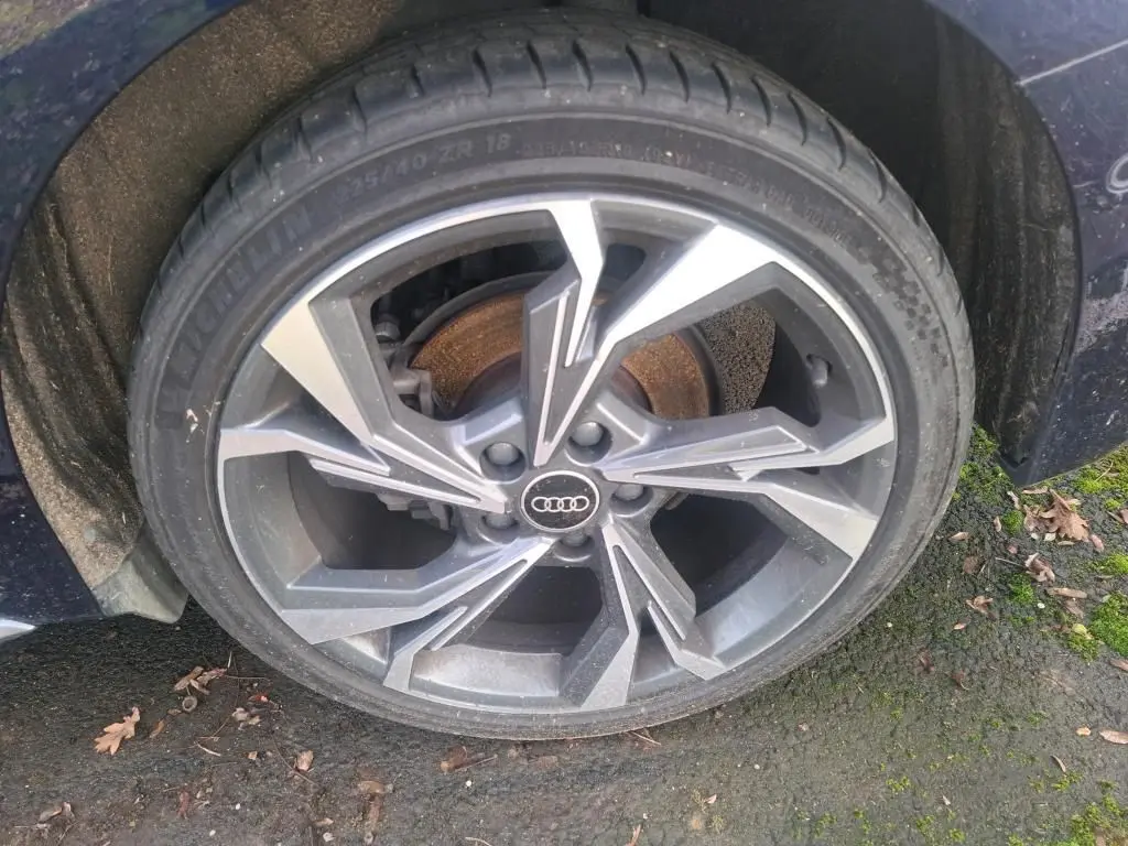 Gros plan sur la roue avant droite d'une Audi A3 2.0 TDI bleu, mettant en valeur la jante alliage au design moderne.