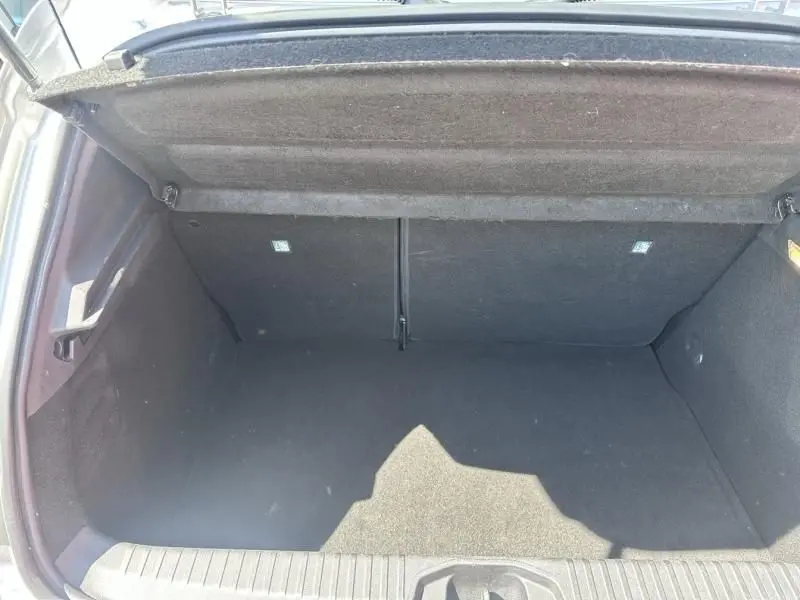 Vue intérieure du coffre ouvert de la Renault Clio V gris métal, montrant un espace de rangement vide et propre.